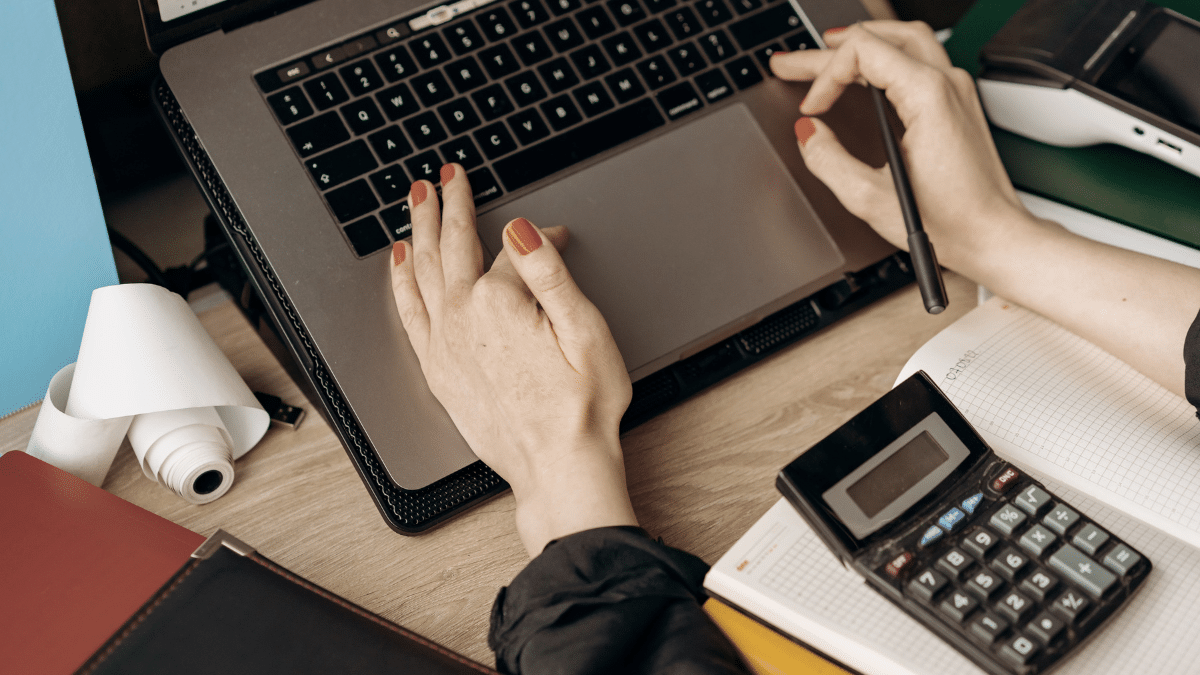 Person checking financial records on a laptop with a statement beside it, representing SMSF trustees reviewing software records.